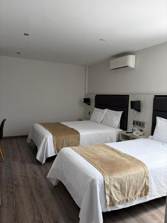 a hotel room with two beds with white sheets at Hotel Nube, Puebla Centro in Puebla
