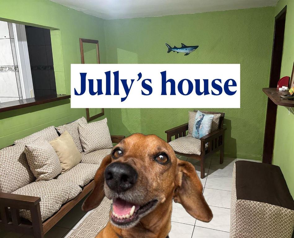 a dog sitting in a living room with a sign at Jully''s house in Arraial do Cabo