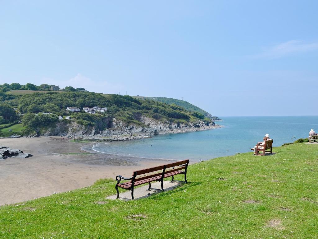 two benches sitting on a hill overlooking the beach at Ty Cornel in Aberporth