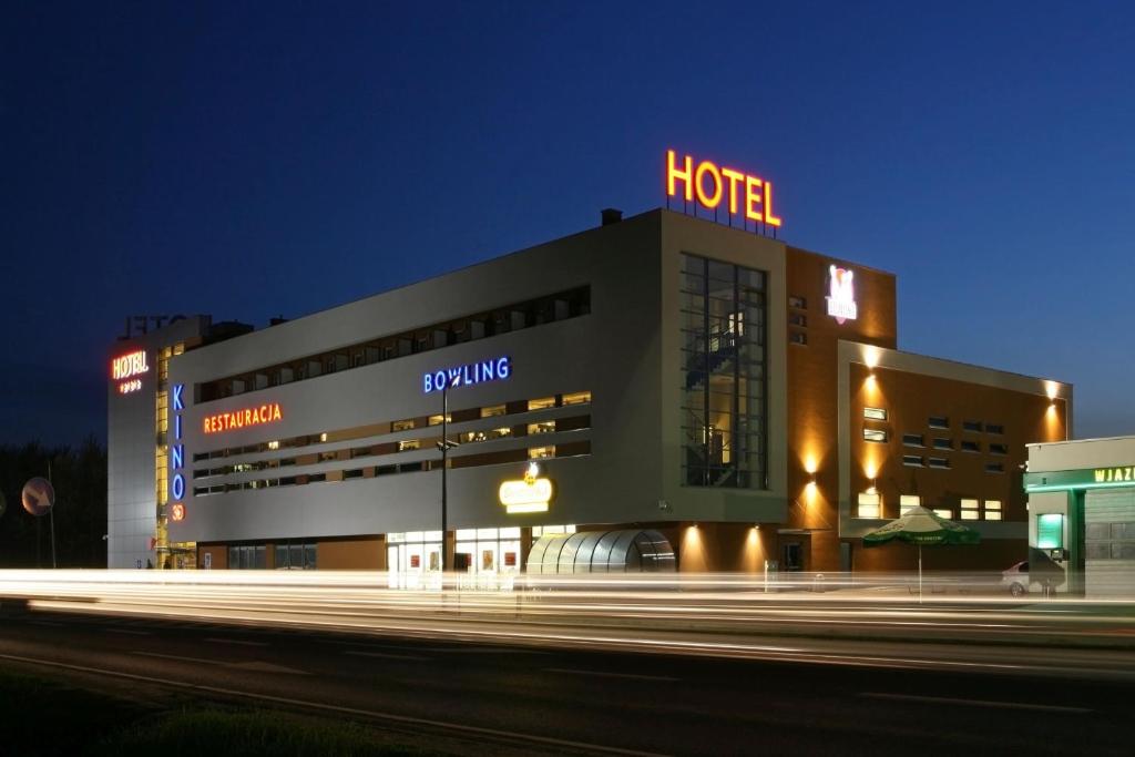 ein Hotelgebäude mit Hotelschild in der Nacht in der Unterkunft QUEST HOTEL - dawniej Hotel Planeta in Brzesko