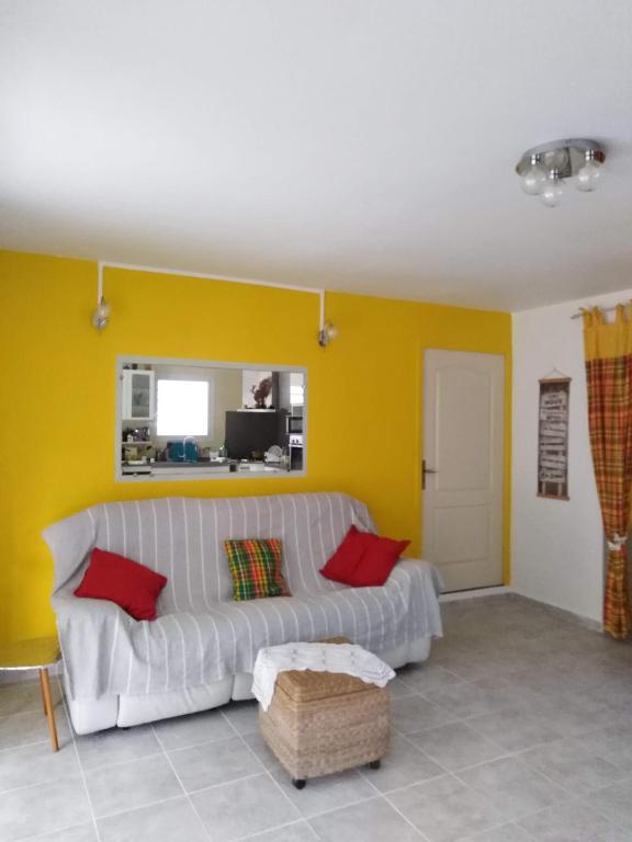 a living room with a white couch and a yellow wall at Villa Madras in Sainte-Anne