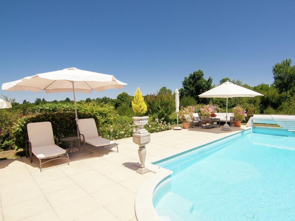 a swimming pool with two chairs and an umbrella at Rouzède Villa with Pool in La Séguinie