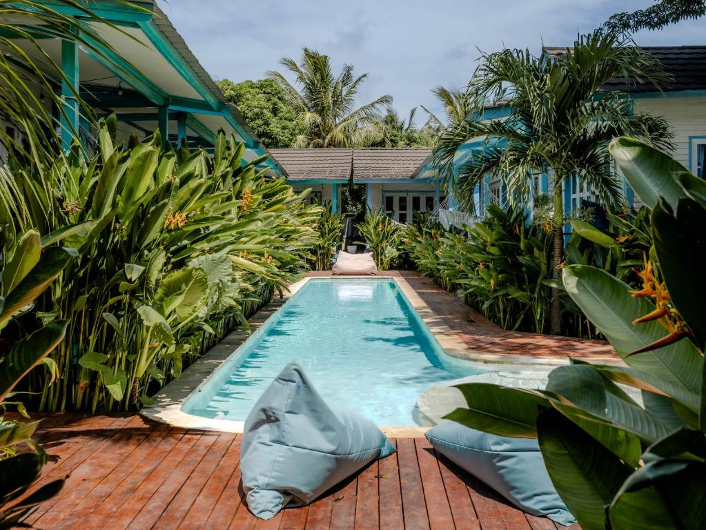 a swimming pool in front of a house with plants at Casa Kapuas in Gili Trawangan