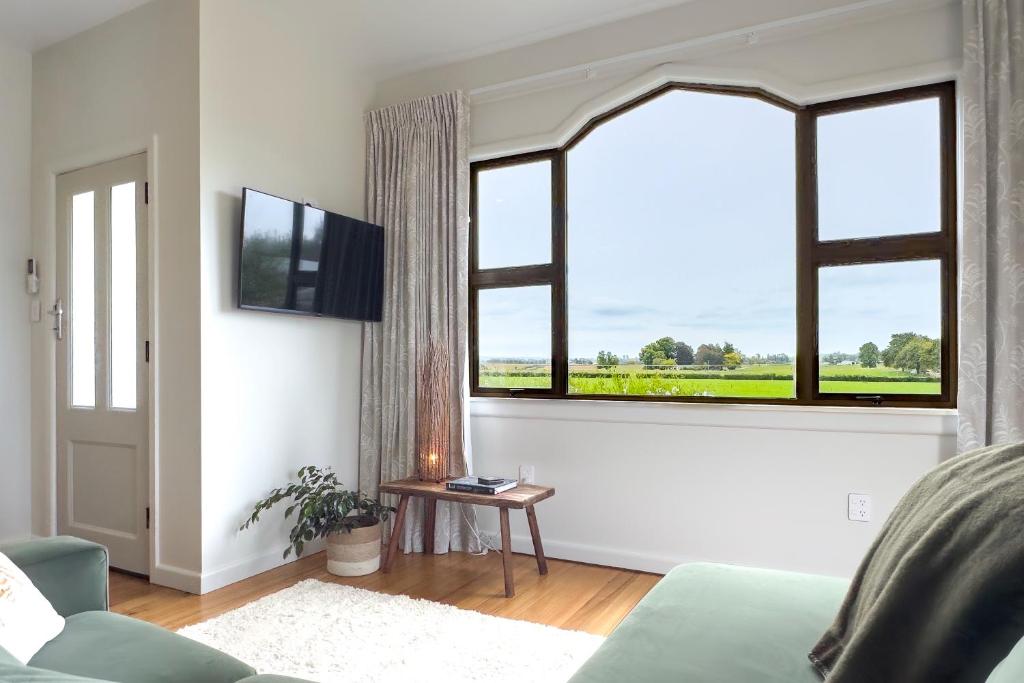 a living room with a couch and a large window at Puna BnB in Matamata