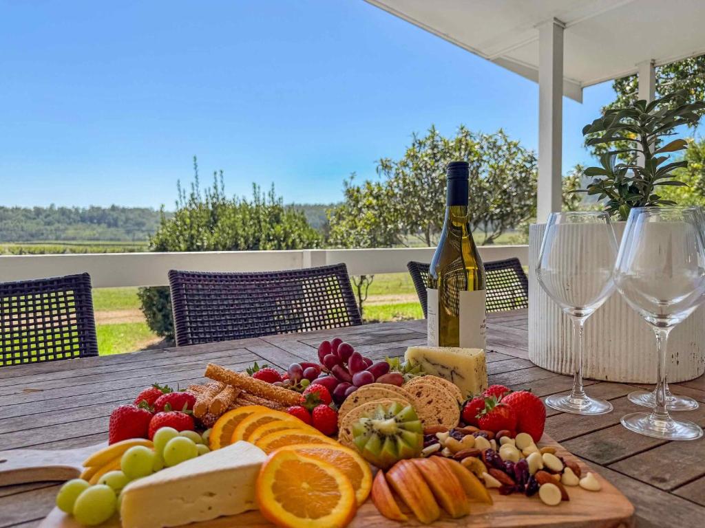a plate of food on a wooden table with wine glasses at The Winegrower's Cottage in Broke