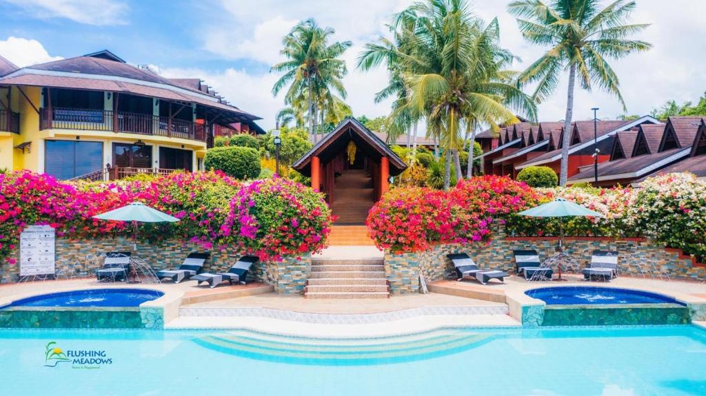 a resort with a swimming pool and a building at Flushing Meadows Resorts & Playground in Panglao Island