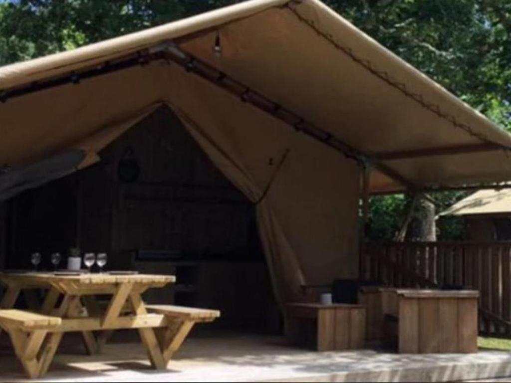 a tent with a wooden table and a picnic table at Tente avec terrasse - 2 pers. - API-1-52-2040 in Grayan-et-lʼHôpital