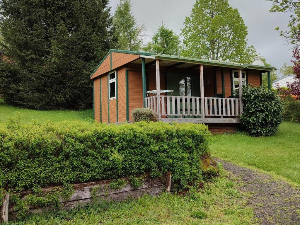 a small house with a porch on a lawn at Chalet avec terrasse - 6 pers. - API-1-52-2030 in La Tour-dʼAuvergne