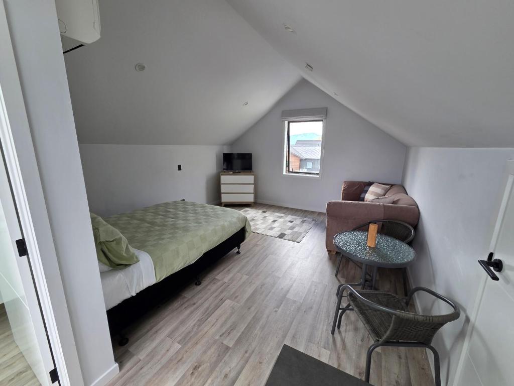 a bedroom with a bed and a chair in a attic at Great Warm Studio Unit in Queenstown Airport