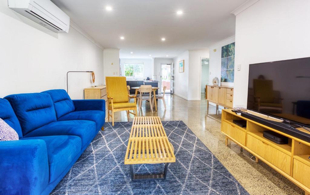 a living room with a blue couch and a flat screen tv at Relax at 42 Cape View Resort in Broadwater
