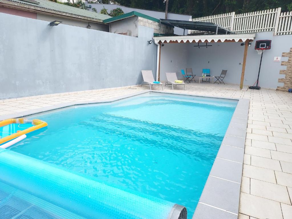 a swimming pool with blue water in a backyard at La créola BAYALOCATION in Rivière-Pilote