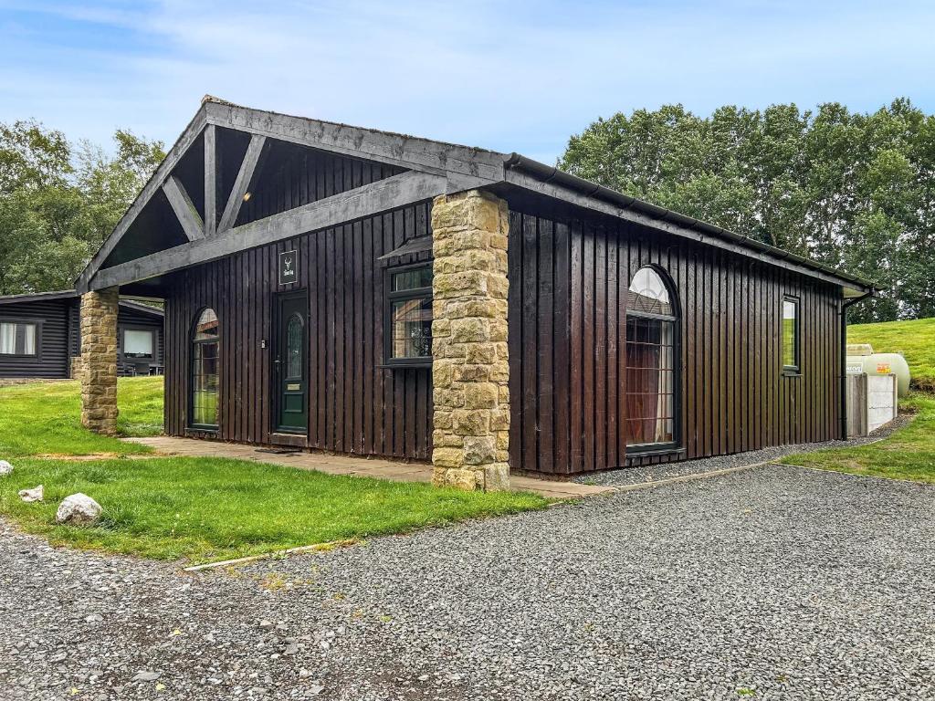 a large wooden building with a stone pillar at The Curious Stag in Rothbury
