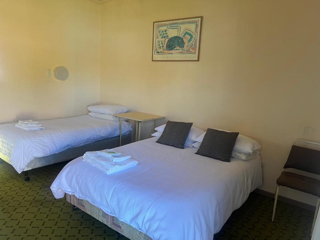 a room with two beds and a table and a chair at Walla Walla Hotel Motel in Walla-Walla
