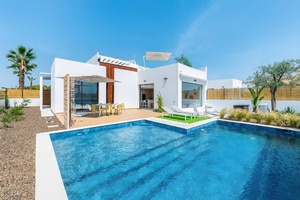 a villa with a swimming pool in front of a house at Edelweiss in Los Alcázares