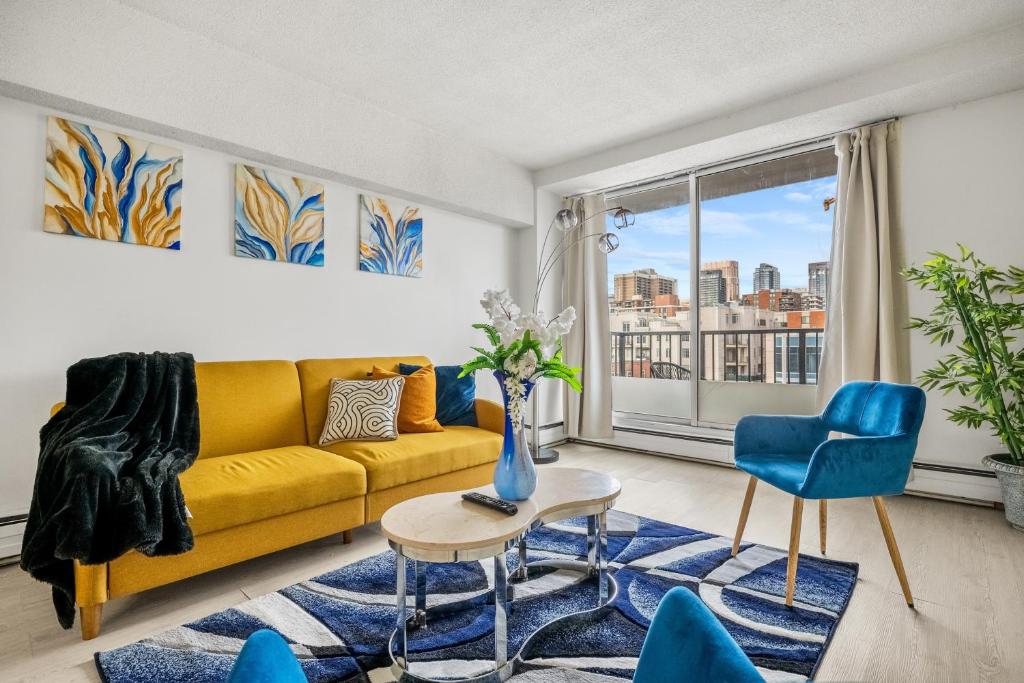 a living room with a yellow couch and blue chairs at 17th Ave Cozy Place in DT, short walk to Calgary Stampede in Calgary
