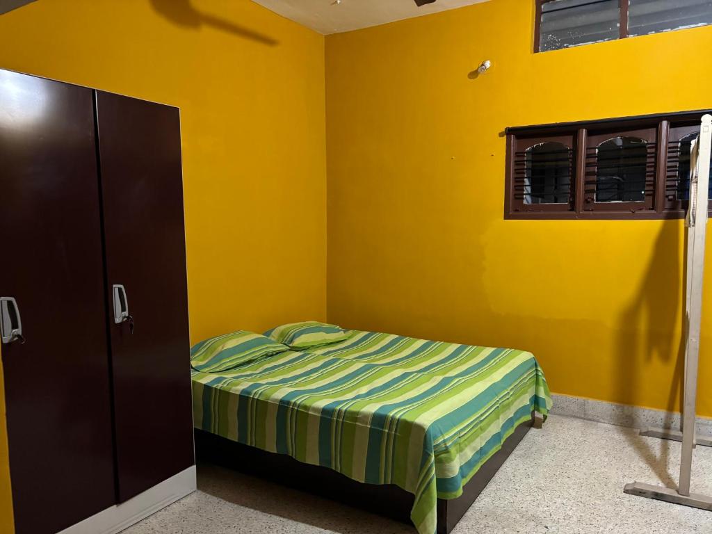 a yellow bedroom with a bed and a window at Untitled Space Residency in Bangalore