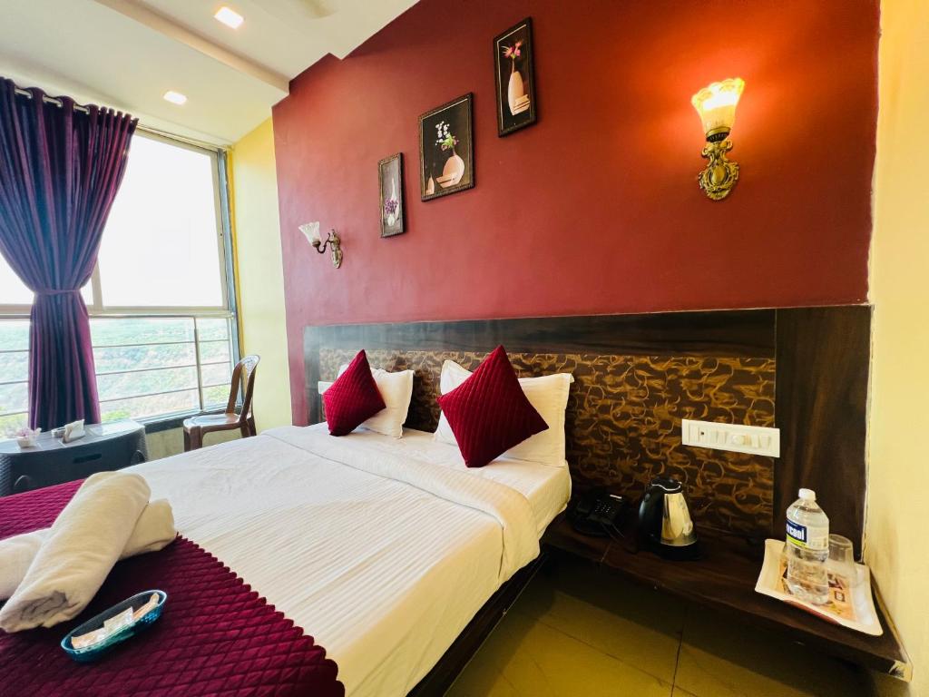 a bedroom with a large bed with red walls at Hotel Nisha in Mahabaleshwar