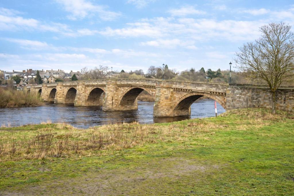 a stone bridge over a river in a city at Corbridge Apartment in Corbridge