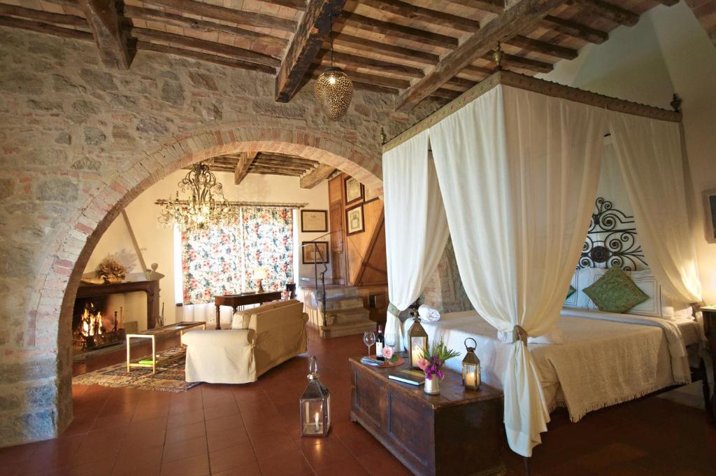 een slaapkamer met een bed en een woonkamer met een open haard bij Pieve di Caminino Historic Farm in Podere Caminino