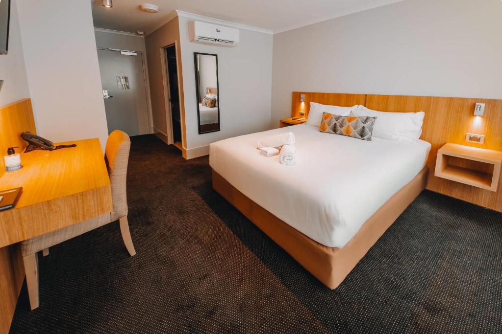 a hotel room with a large bed and a desk at Clarion Hotel Townsville in Townsville