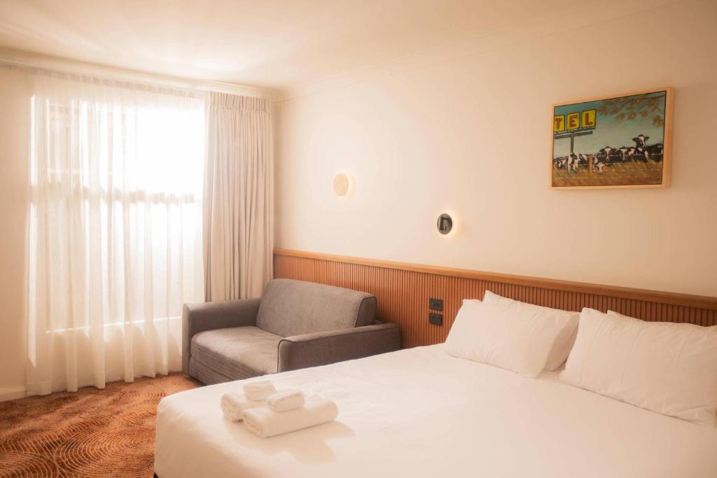 a hotel room with a bed and a chair at The Alluna Motel, an Ascend Collection Hotel in Armidale
