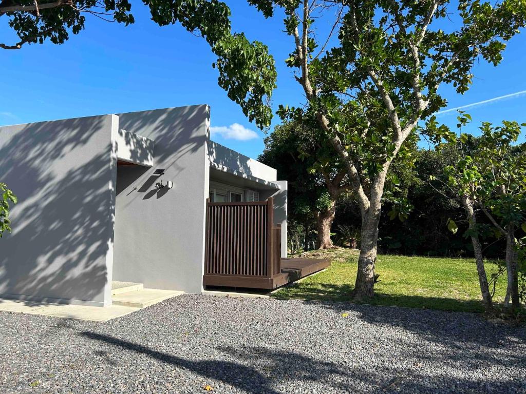 a white house with a wooden door and a tree at リベルテ Work & Vacation Villa Nosoko in Ibaruma