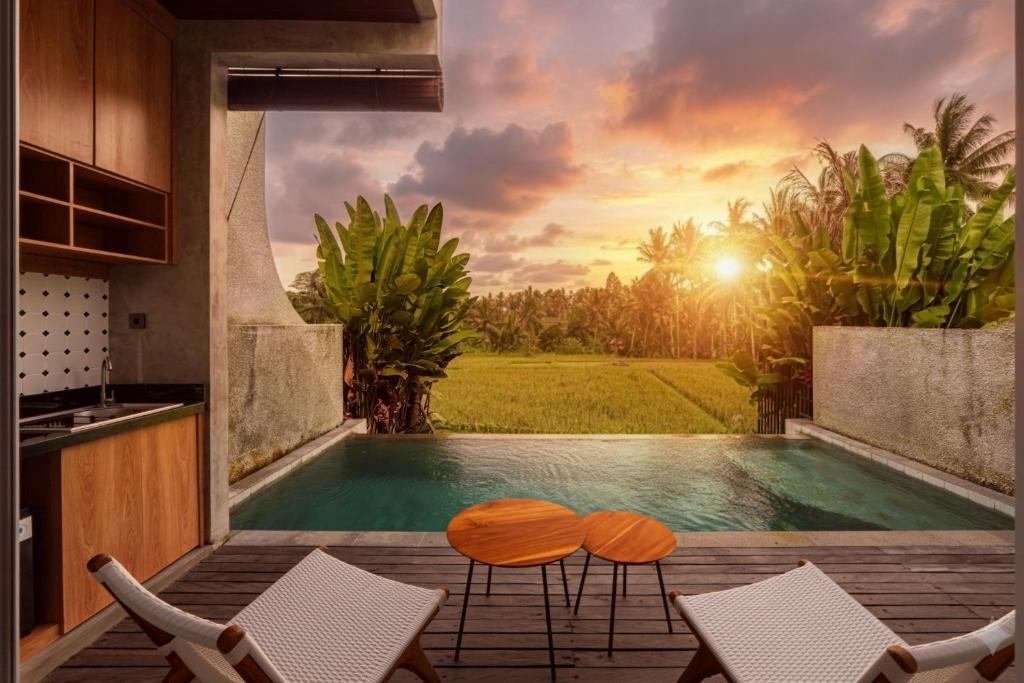 a swimming pool in a villa with a sunset at Subu Utamas Villas in Ubud