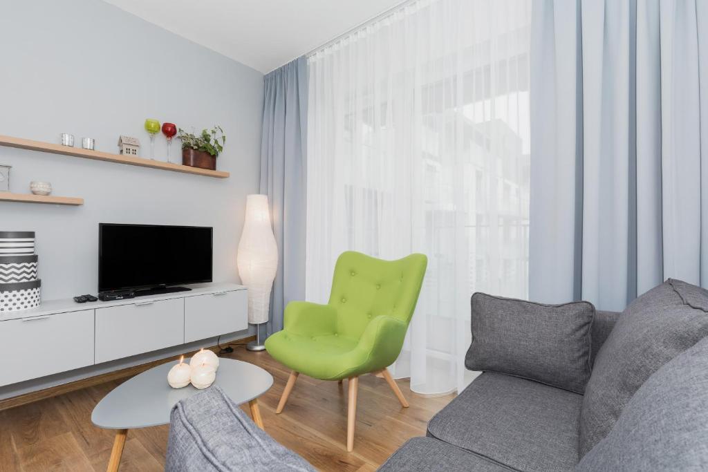 een woonkamer met een bank en een groene stoel bij Apartamenty Morski Florek in Kołobrzeg