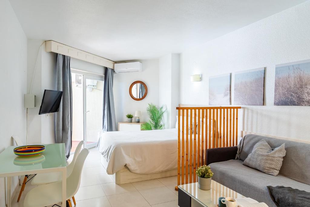 a hotel room with a bed and a couch and a tv at nice seafront apartment in Almuñécar