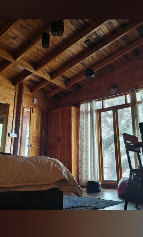 a bedroom with a bed and a large window at wood house vattakanal in Kodaikānāl