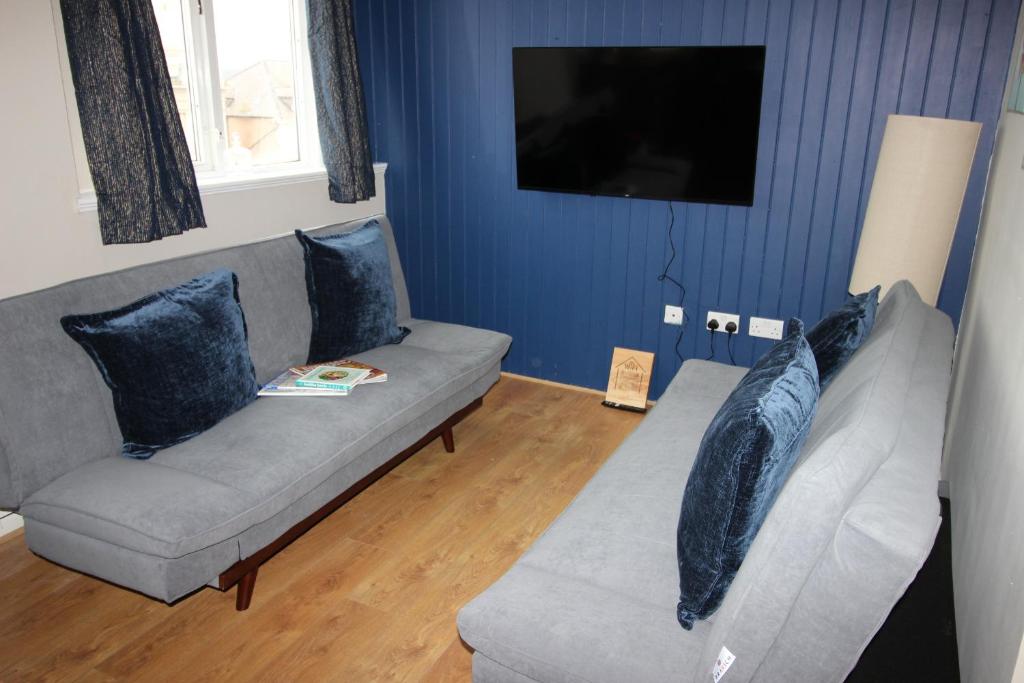 a living room with a gray couch with blue pillows at Cornerhouse Apartments 4 Sleeps 5 in Llandudno