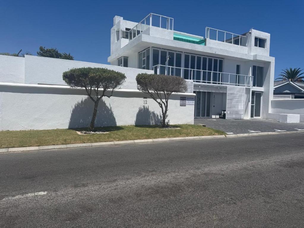 a white building with two trees in front of it at Skypool Guesthouse in Cape Town