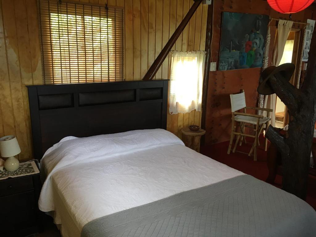 a bedroom with a bed and a table and a chair at Cabañas Moai in Hanga Roa