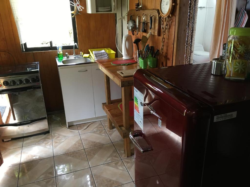 a kitchen with a refrigerator and a table in it at Cabañas Moai in Hanga Roa