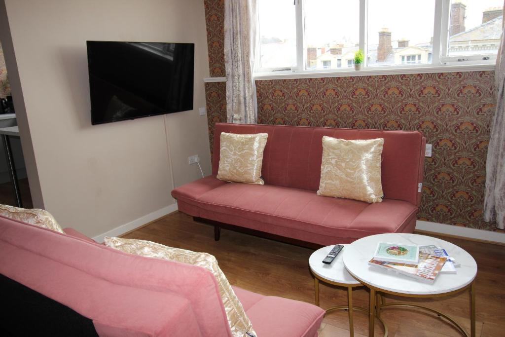 a living room with a red couch and a table at Cornerhouse Apartments 5 Sleeps 5 in Llandudno