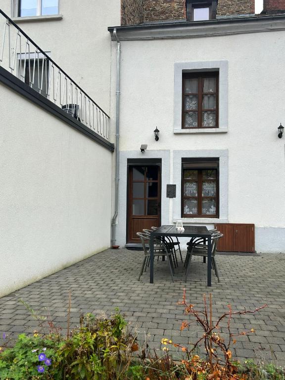 a patio with a table and chairs in front of a building at Chez Germaine in Bouillon
