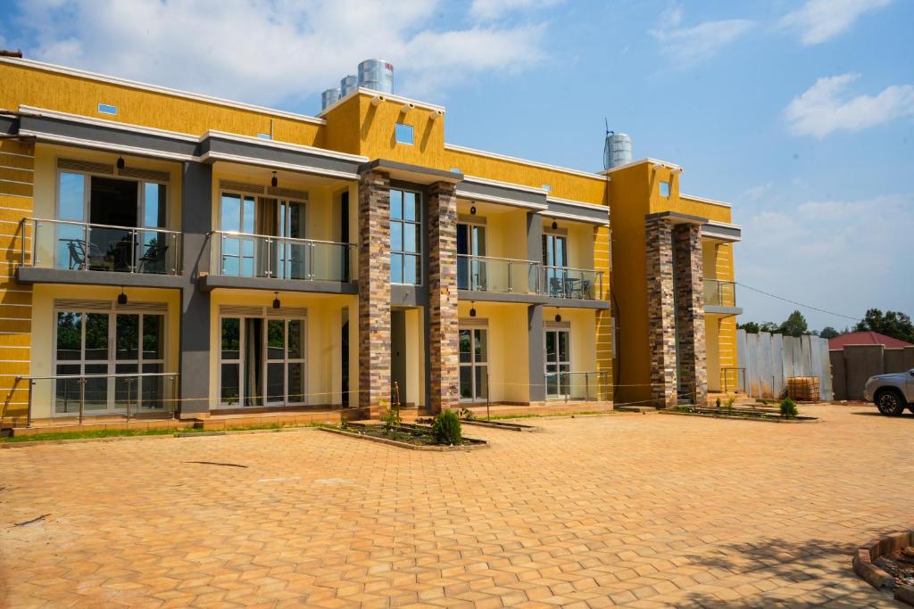 a large yellow building with a brick courtyard at Cosy Homes in Gulu