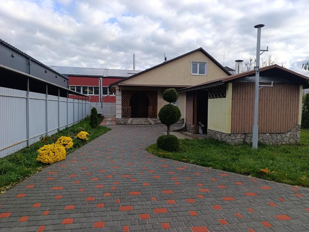 a house with a brick walkway next to a building at Гостьовий будинок з банею in Bohuslav