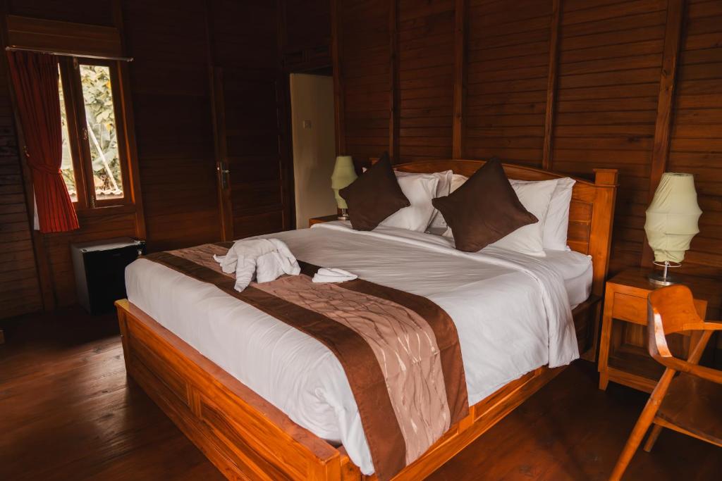 a bedroom with a large bed with white sheets and pillows at Munduk Seming Cottages in Munduk