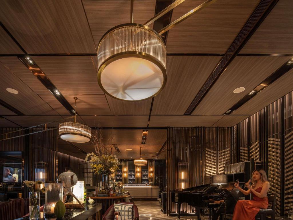 A warmly lit lobby with a bar, piano, lounge seating, and sculptural pendant lights.