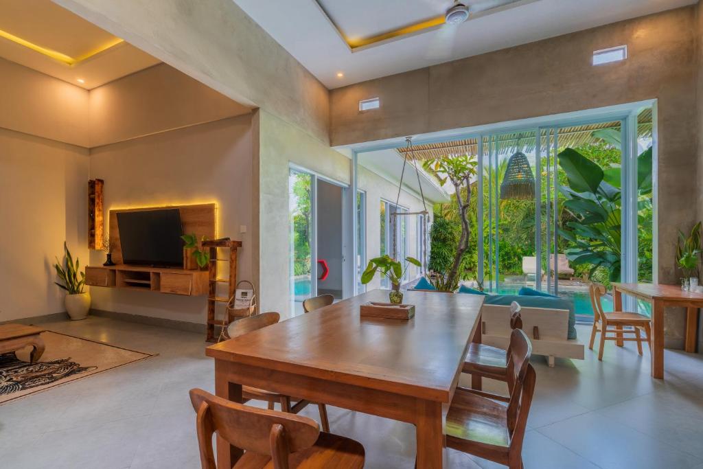 a living room with a wooden table and chairs at Gemello Bali Villa in Keramas