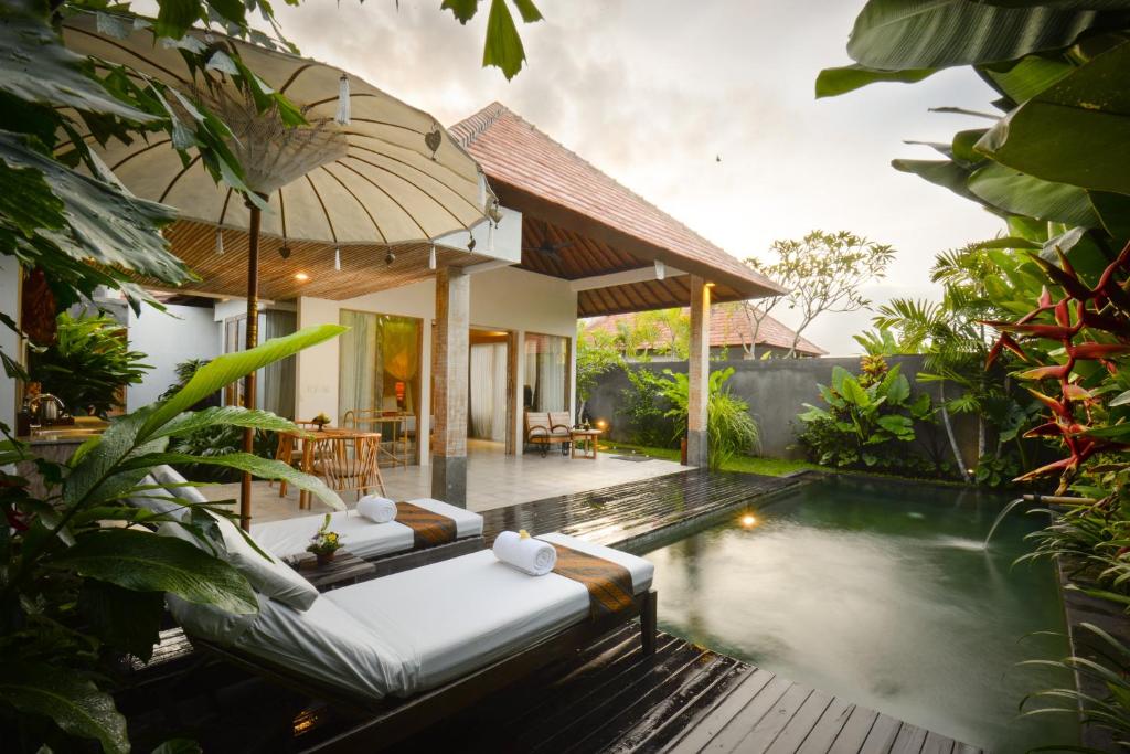 a villa with a swimming pool in a garden at Purana Boutique Resort in Ubud