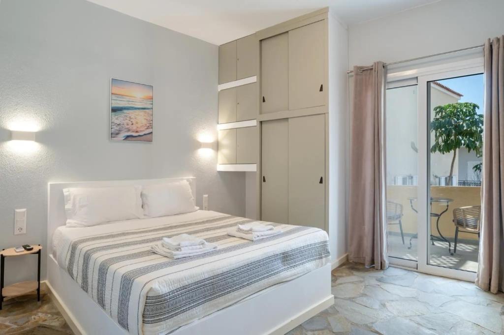 a white bedroom with a bed and a balcony at Ariston House in Porto Heli
