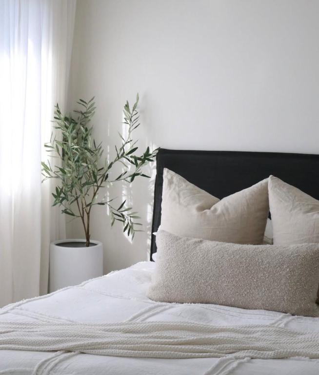 a bed with white sheets and a plant in a bedroom at Private big ROOM 20mins to Airport, 5mins to station in St Albans