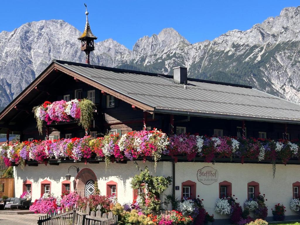 a building with flowers on it in front of mountains at Appartement & Ferienwohnung am Baby & Kinderbauerhof Stefflhof in Saalfelden am Steinernen Meer