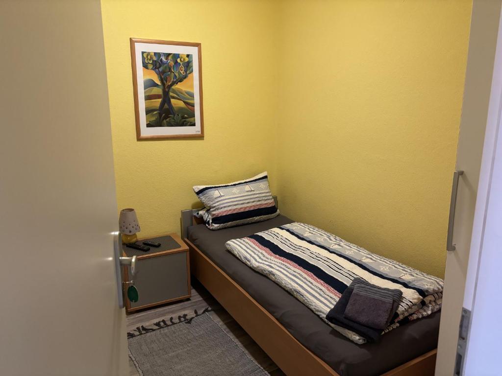 a small bedroom with a bed in a yellow wall at Möllers Morgen in Lentföhrden