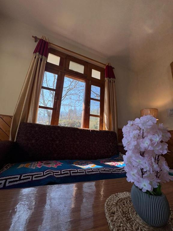 a living room with a couch and a vase with flowers at Walking Trails Homestay in Baragrān