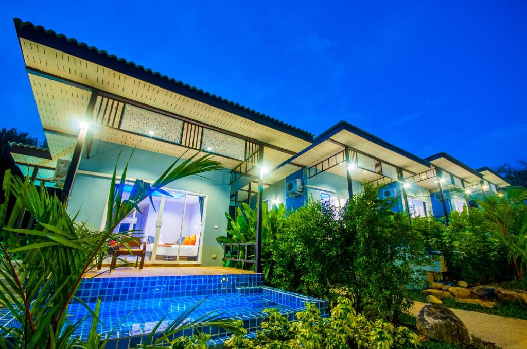 a house with a swimming pool in front of it at Chomphu Resort in Khao Lak