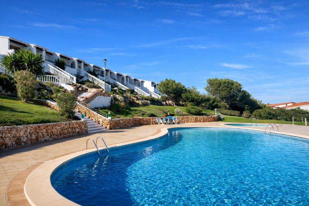 a swimming pool in front of a building at Apartamento Ada a 2 minutos de la playa y con piscina! in Arenal d'en Castell