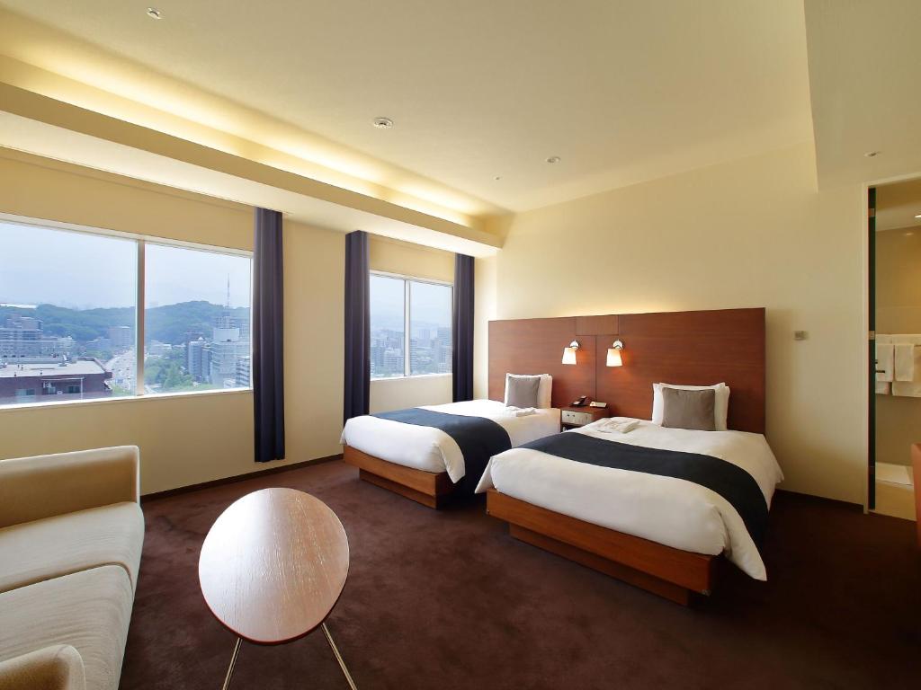 ein Hotelzimmer mit zwei Betten und einer Couch in der Unterkunft Oriental Hotel Hiroshima in Hiroshima